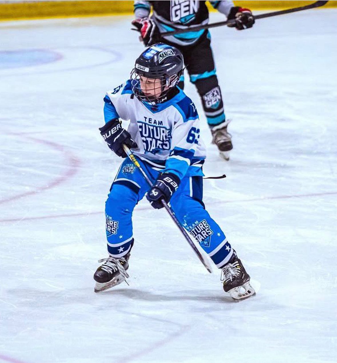 A Team Future Stars player in a white and blue jersey drives up the ice with the puck