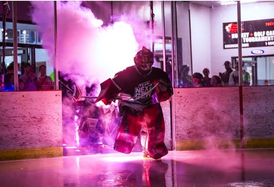 A young Coast 2 Coast player skates out through pink smoke and arena lights during the tournament's player introductions